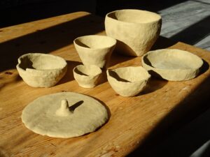 Homemade clayworks drying in the sun on a wood plank - Ouvrages de poterie en argile fait maison séchant au soleil sur une planche de bois